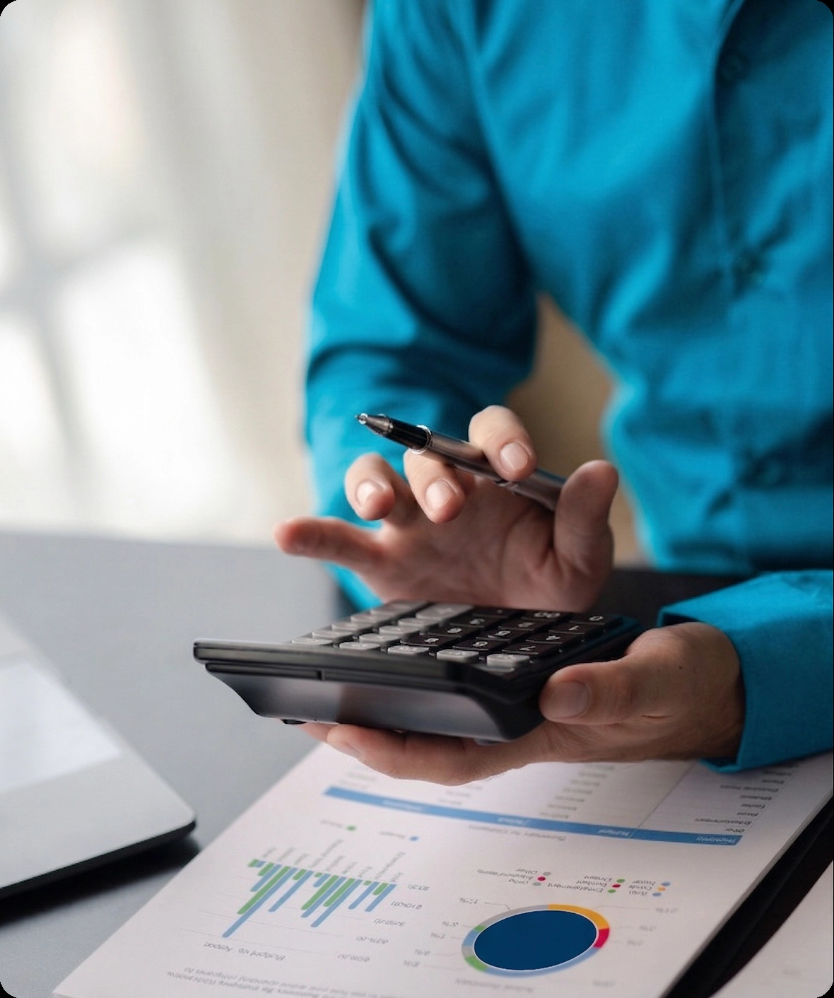 A professional using a calculator to analyze financial charts for a business loan capital assessment.